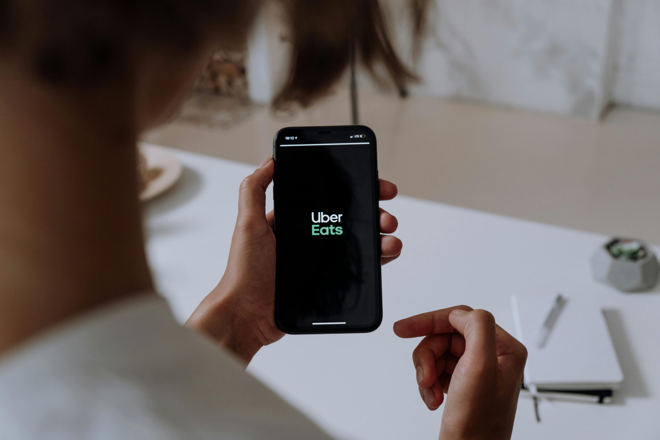 Person holding a smartphone using Uber Eats. Indoor setting with a clear view of the app interface.