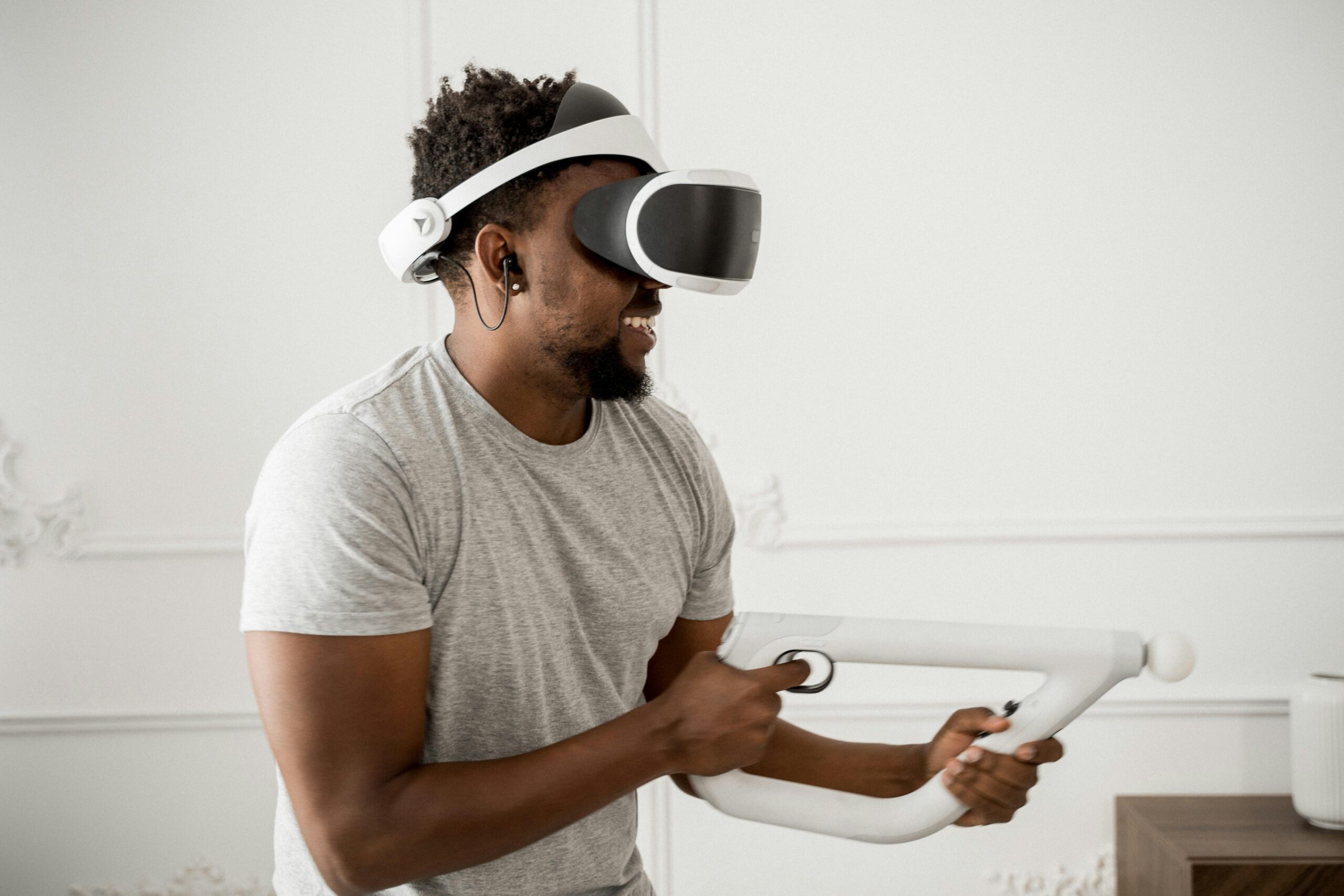 Smiling man playing with VR headset and controller, enjoying immersive experience.
